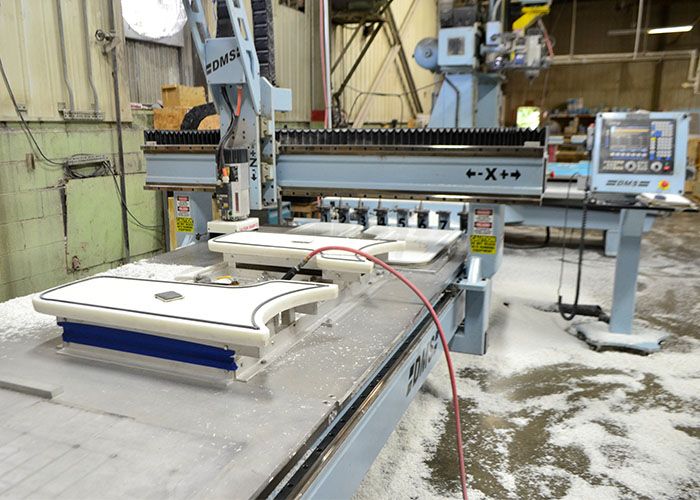 CNC router trimming white parts on a vacuum table
