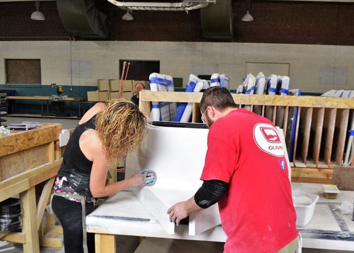 Two technicians hand finishing a white fiberglass part