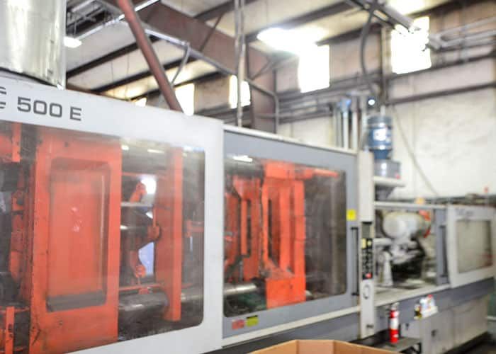 Large injection molding machine with orange safety guards