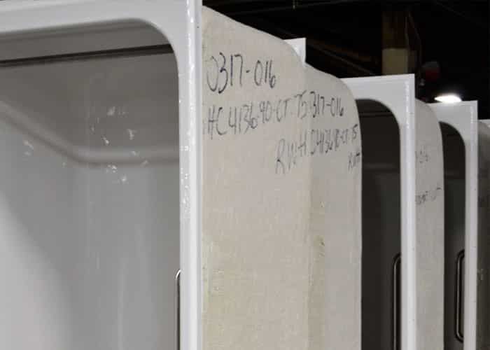 Row of molded fiberglass shells with handwritten job numbers