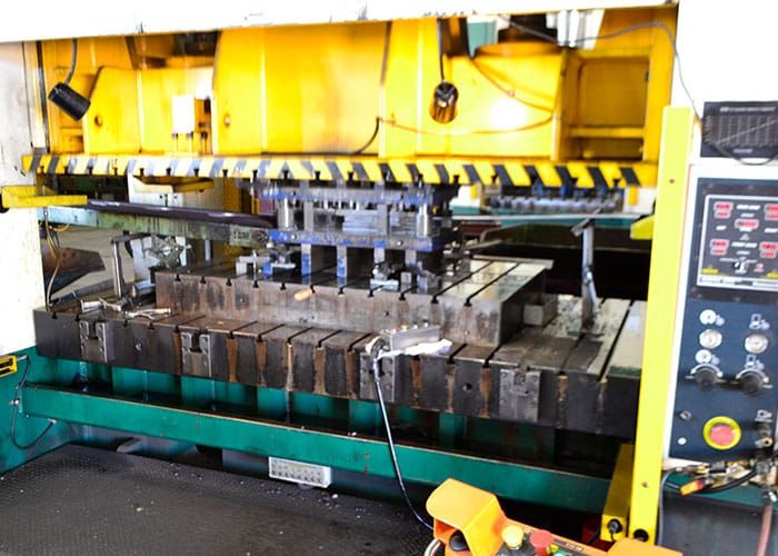Yellow stamping press with a die set on the bed