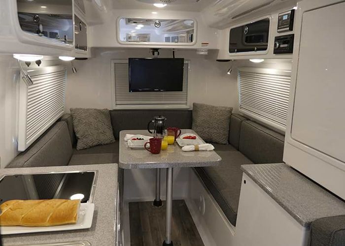 Molded fiberglass interior of an Oliver travel trailer with a dinette and overhead cabinets
