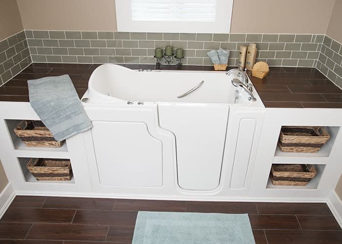 Walk-in tub built into a tiled alcove with open shelving on both sides